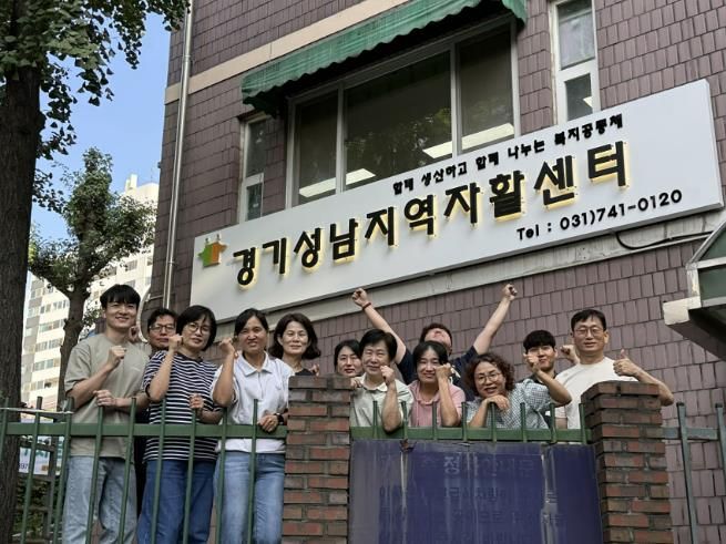 보건복지부 평가 최우수 기관으로 선정된 성남지역자활센터 관계자들이 센터 정문 앞에서 기념사진을 찍고 있다.