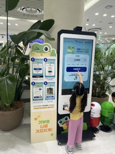 한 어린이가 기부 키오스크 활용해 기부를 하고 있다.